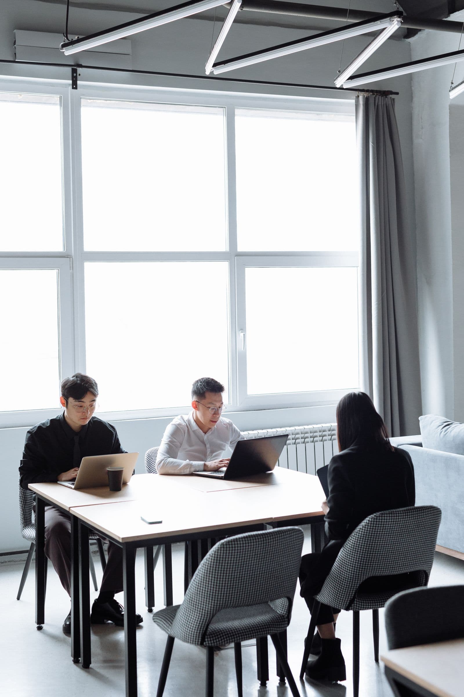 Team members collaborating on laptops in a bright modern office